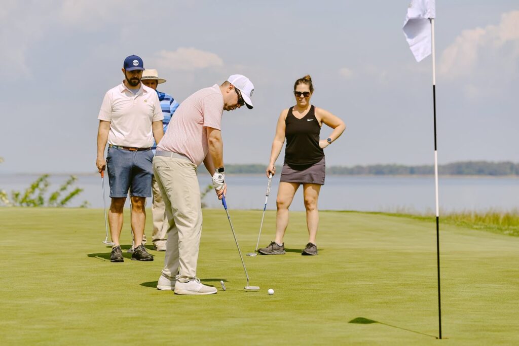4 people putting on a green with the water behind them