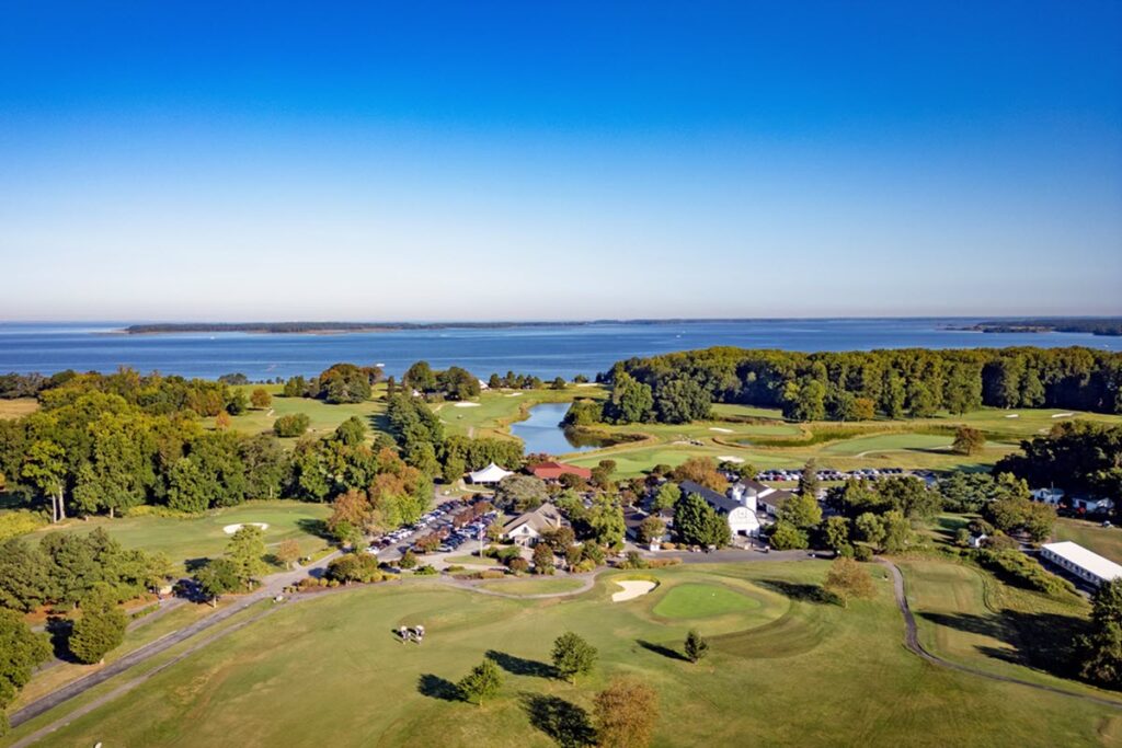 Drone shot from above Queenstown golf course showing the building surrounded by the golf course and the Chesapeake Bay