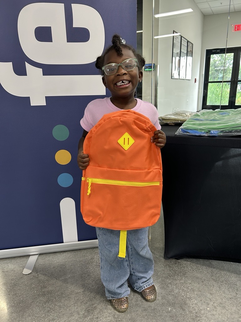 Little girl with a BIG smile holding her new backpack