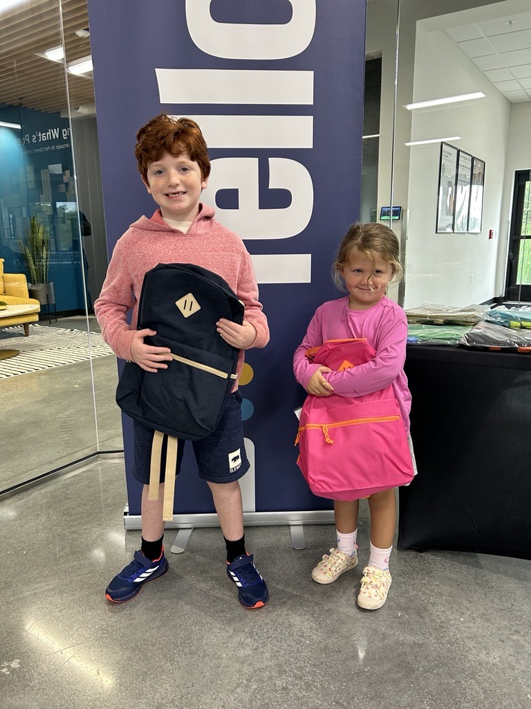 A little boy and little girl holding their new backpacks at the back to school event