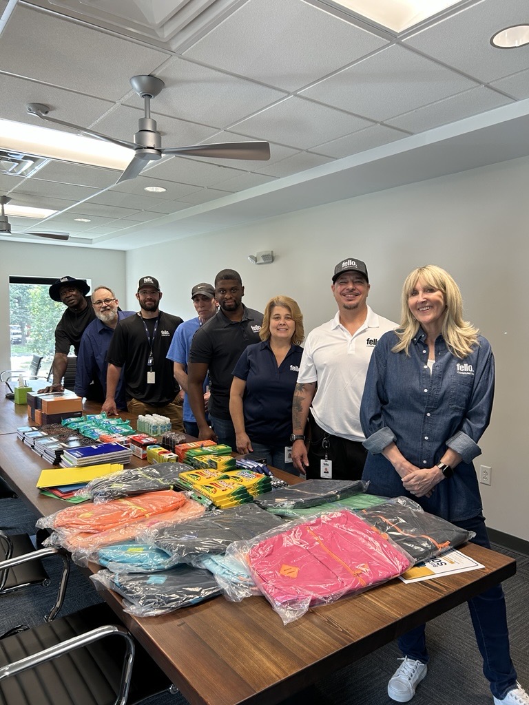 Fello Communities team members standing in front of a table full of school supplies
