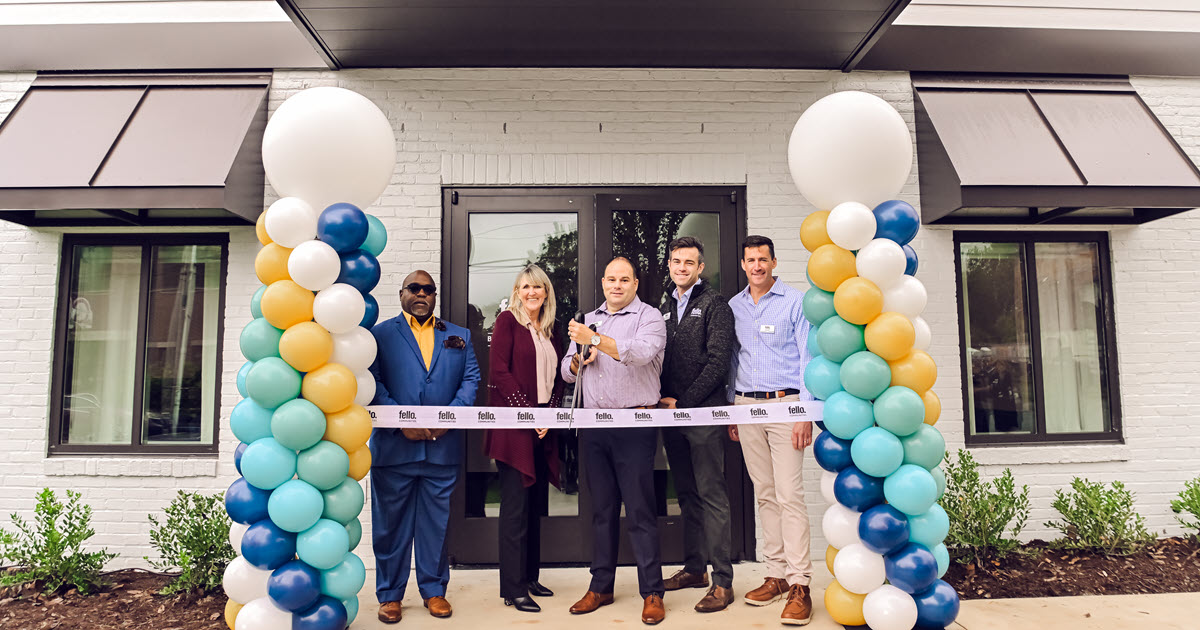 Five people standing in the doorway of the new Leasing Office getting ready to cut the ribbon