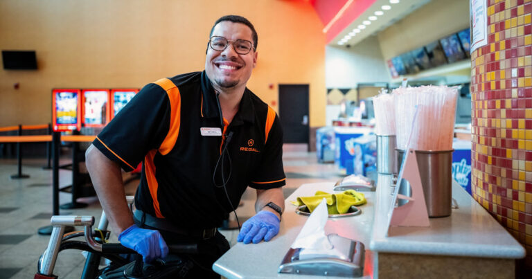 October is National Disability Employment Awareness Month (NDEAM) - man smiling while working at a movie theater and cleaning a counter