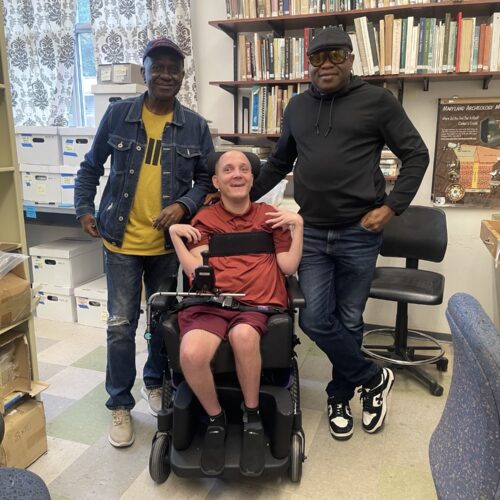 Two people standing next to a person in a wheelchair posing for a picture