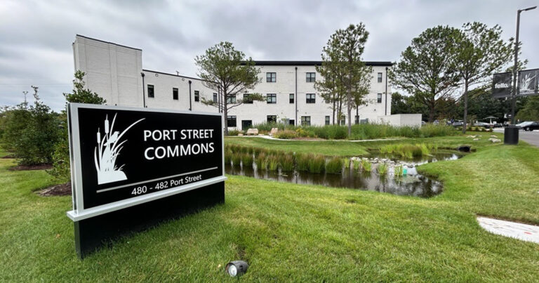 White three-story building with beautiful landscaping and a sign in the foreground that reads Port Street Commons 480 - 482 Port Street