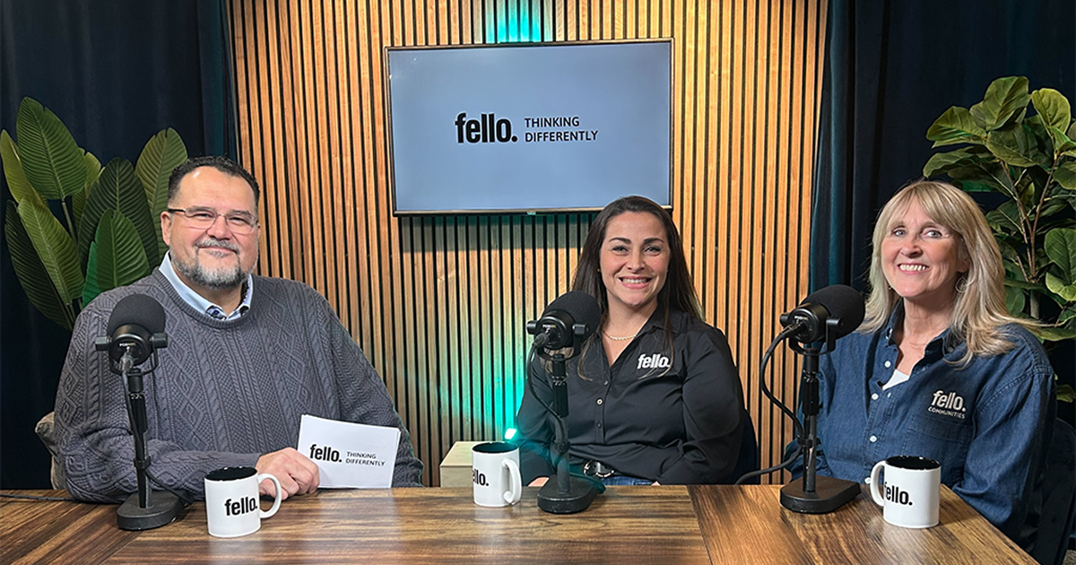 Three people sitting at a desk for a podcast.
