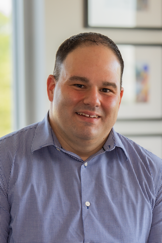 Jonathon Rondeau, President & CEO headshot. He's wearing a blue and white shirt smiling for the camera