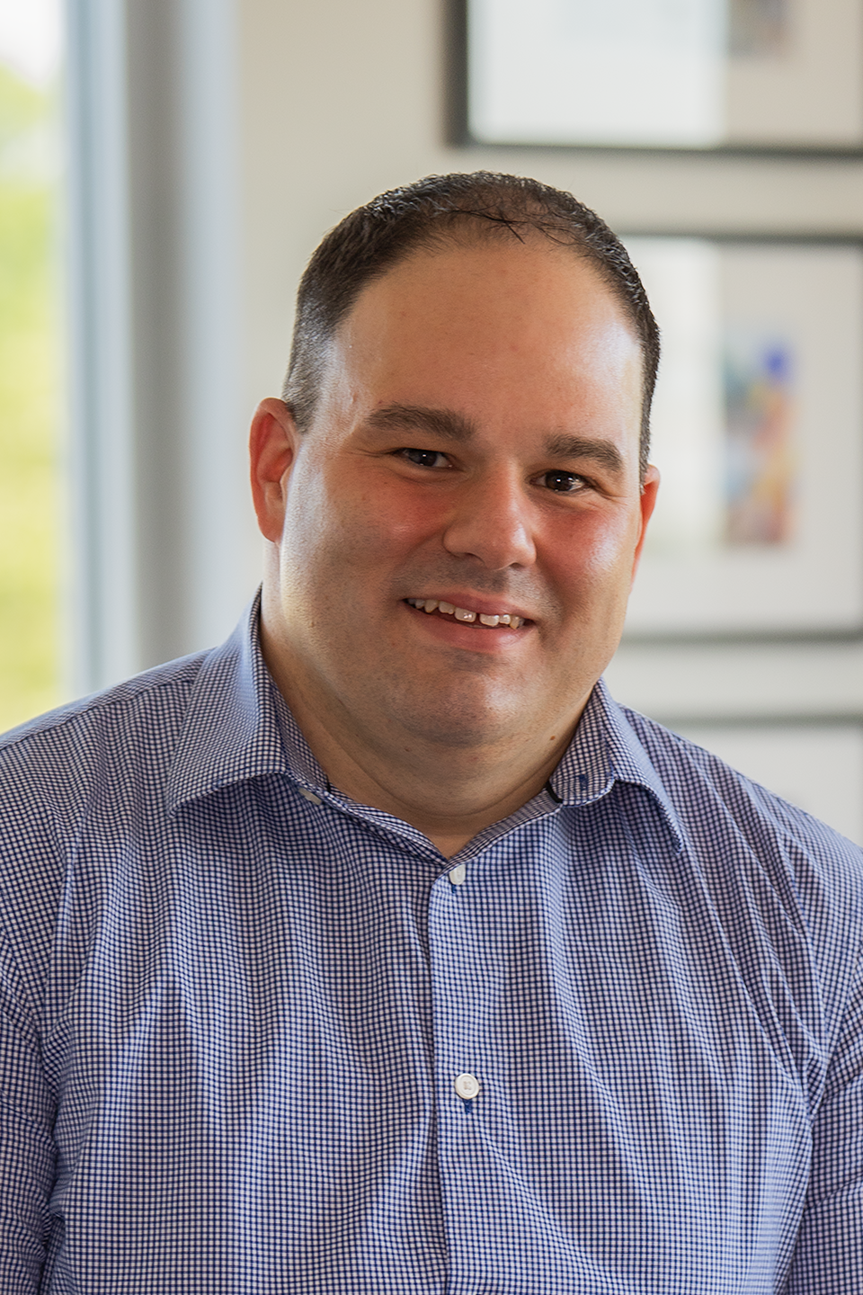 Jonathon Rondeau, President & CEO headshot. He's wearing a blue and white shirt smiling for the camera