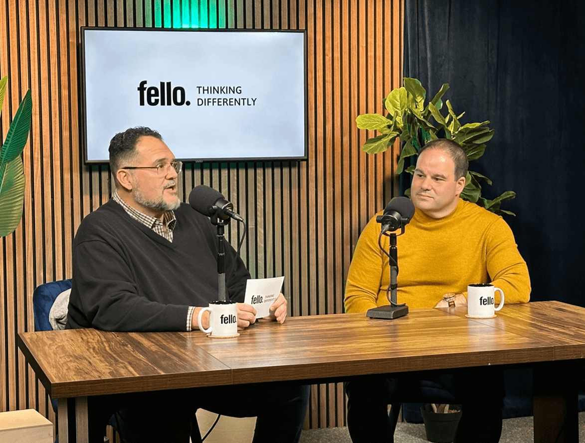Two people having a conversation at a desk with microphones, featuring "Fello. THINKING DIFFERENTLY" branding and celebrating Fello's 65th Anniversary. The discussion is titled "A conversation with Jonathon Rondeau." The setting includes a green striped background and the desk displays the Fello logo.