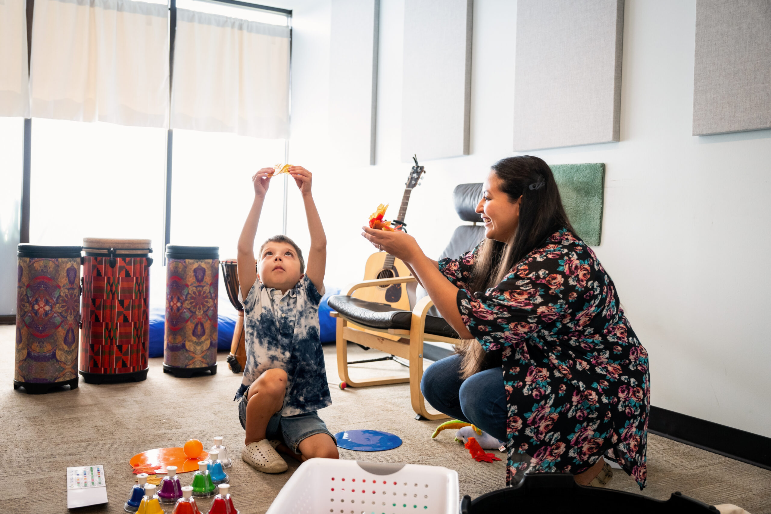 A young boy and woman in a music room setting working on music therapy.