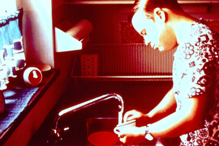 A person washing a cup in his own home in the 1970s.