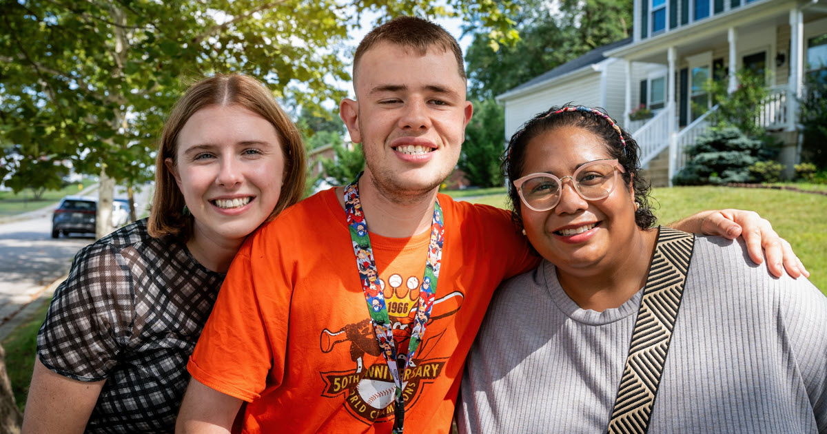 Three people standing close together almost hugging smiling for the camera
