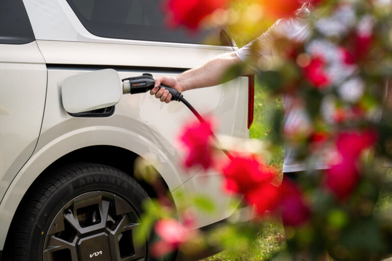 Person plugging in an electric charging port to a vehicle as part of Fello's sustainability plan.