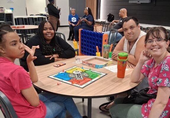 Four people sitting at a table playing board games.