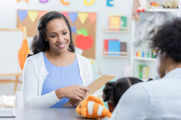 A teacher holding a clip board to take notes during an IEP meeting