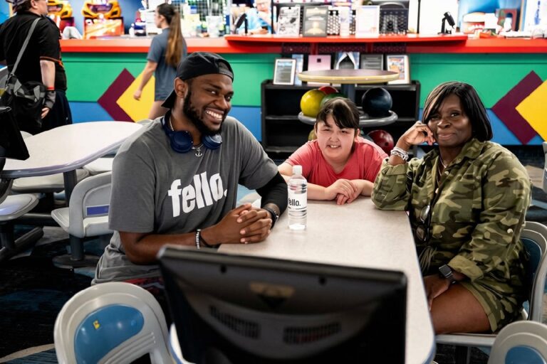 Three people sitting at a table in a bowling alley