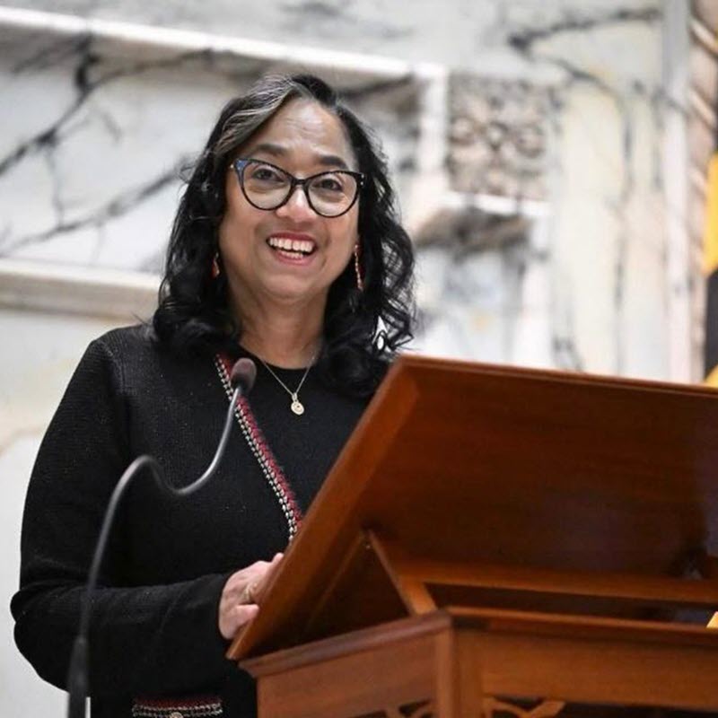Joseline Peña-Melnyk, Maryland House Speaker speaking at a podium wearing a black dress. 
