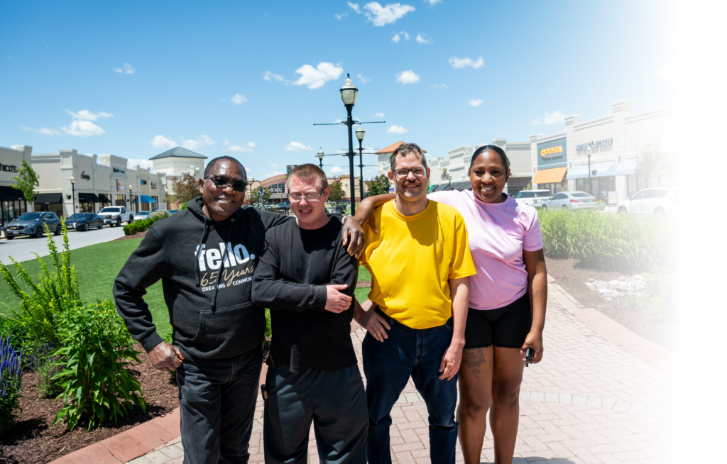 Four people standing in a group at a shopping center smiling for the camera