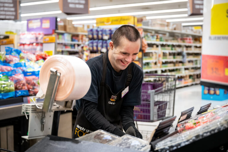 Person working in a grocery store stocking vegetable.