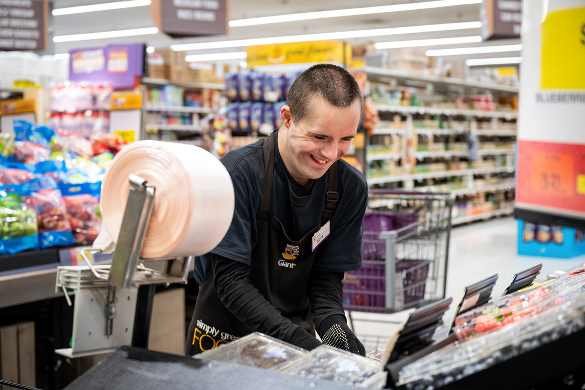 Person working in a grocery store stocking vegetable.