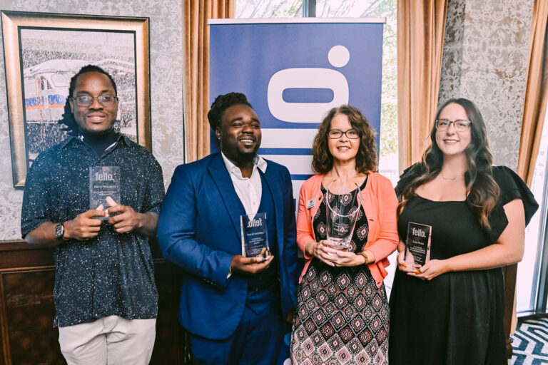 Two men and two women standing together holding awards at an event