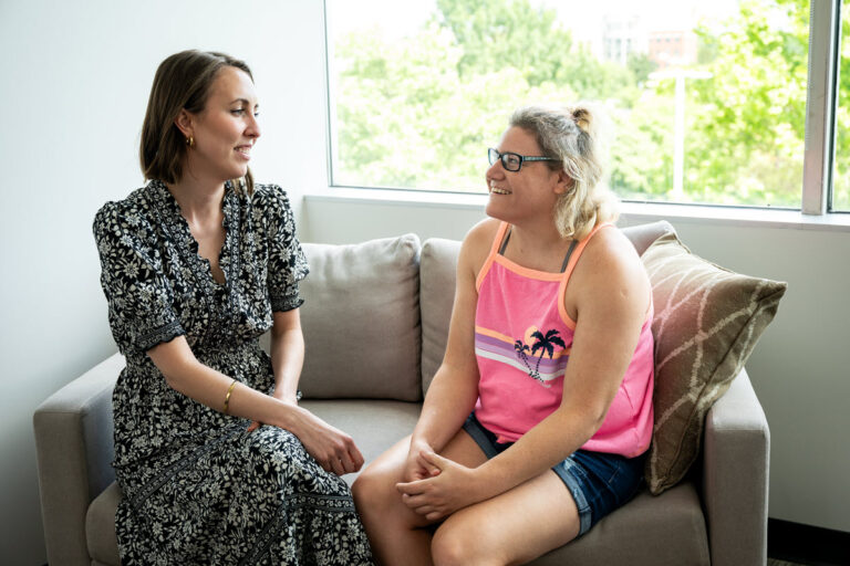 Two people sitting on a couch talking to each other.