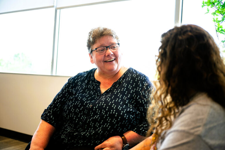 a woman sitting at a table talking to another person