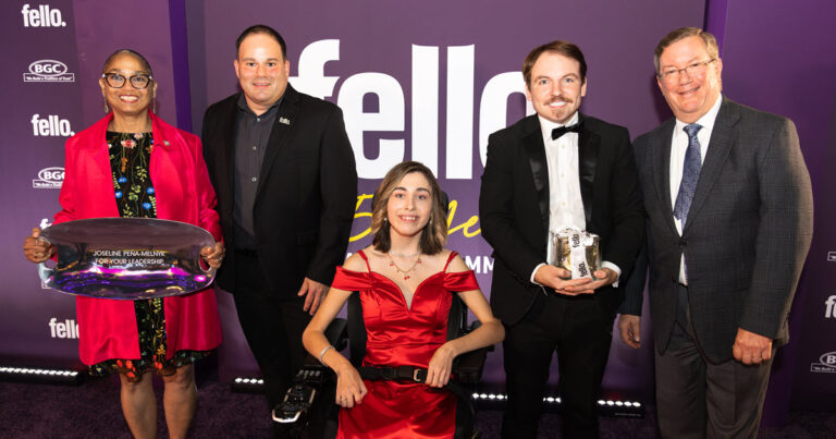 4 people standing and person in wheelchair as a group in front a Fello sign with two people holding awards