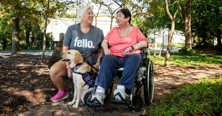 a woman in a wheelchair with a support dog and the dog's handler