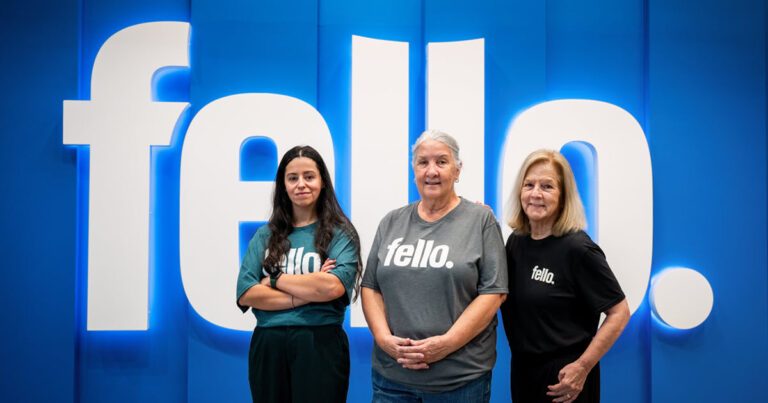 Three people standing in front of a Fello sign while wearing Felle shirts