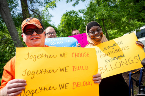 a group of people holding up yellow signs for a rally